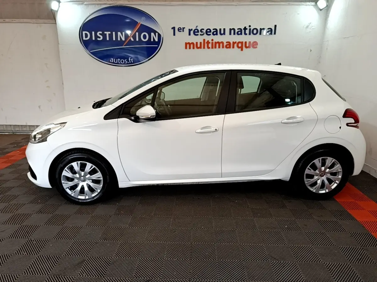 Profil côté gauche d'une Peugeot 208 blanche Puretech 82 S&S Active Business de 2018, dans un showroom intérieur.