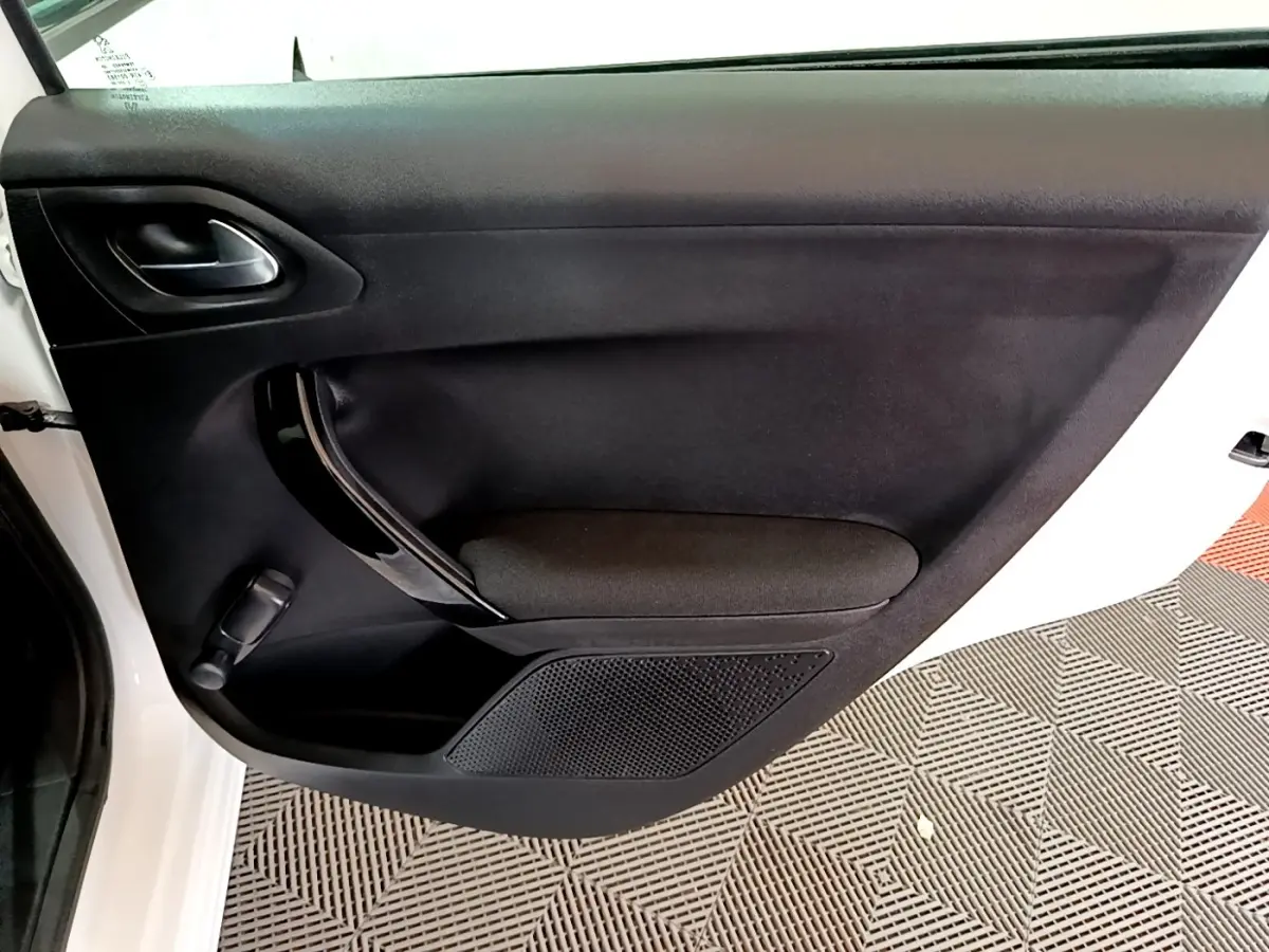 Vue rapprochée de la porte avant gauche noire d’une Peugeot 208 blanche, avec poignée et commande de vitre manuelle.