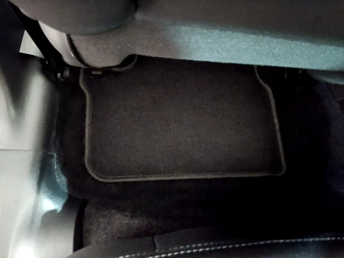 Vue rapprochée du tapis de sol noir sous le siège arrière d’une Peugeot 208 blanche de 2018.
