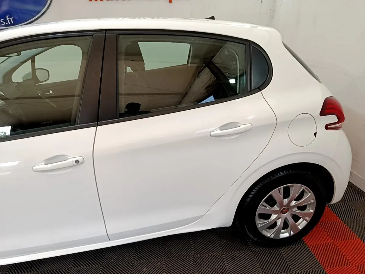 Vue latérale côté droit d'une Peugeot 208 blanche, mettant en valeur la portière arrière et la roue arrière.