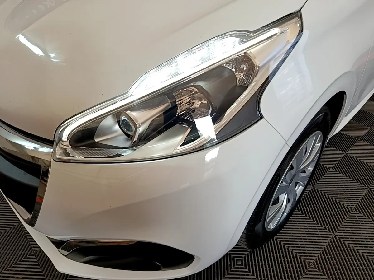 Gros plan sur l’avant droit blanc d’une Peugeot 208 2018, mettant en valeur le phare et la roue.