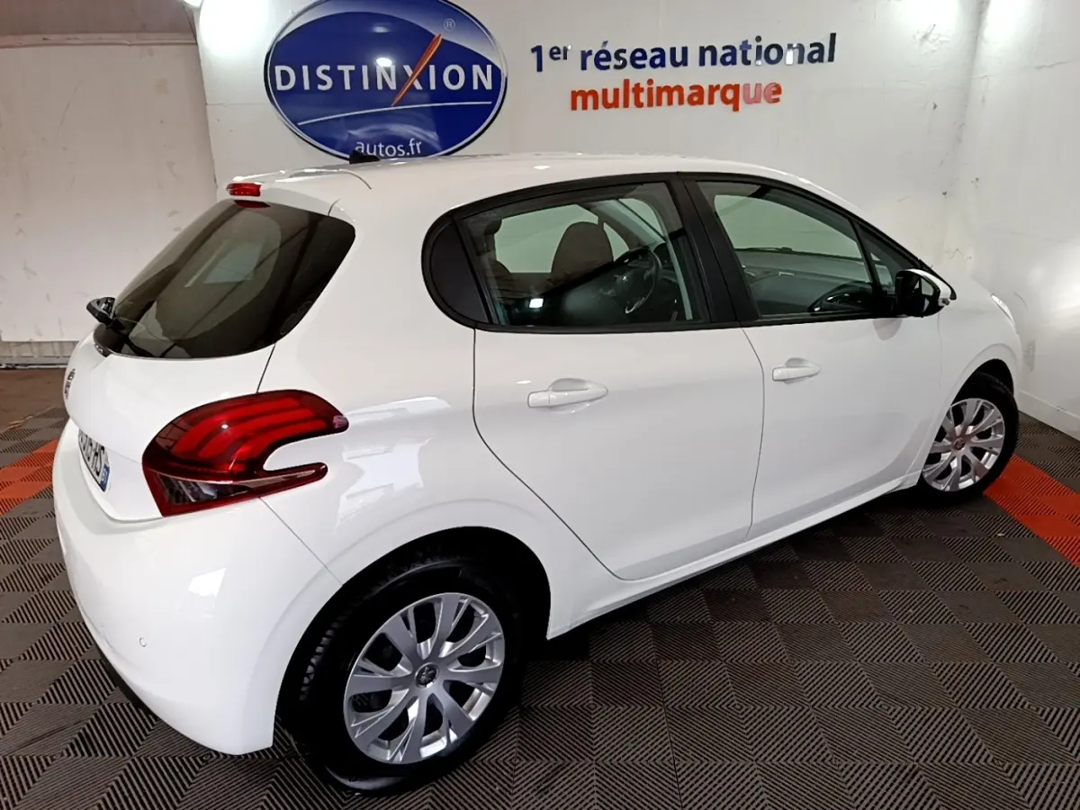 Vue 3/4 arrière droite d'une Peugeot 208 blanche Puretech 82 S&S Active Business en intérieur showroom.