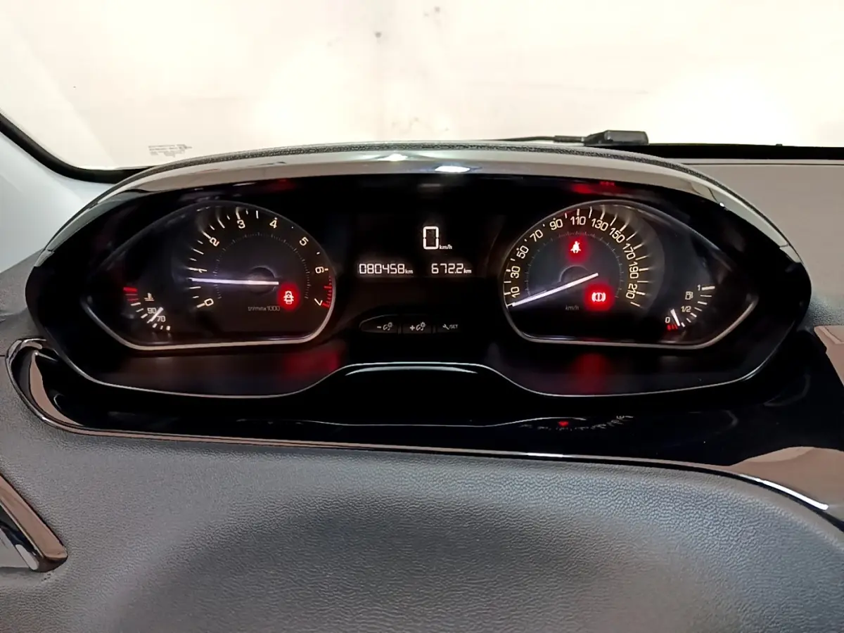 Vue rapprochée du tableau de bord numérique de la Peugeot 208 blanc, affichant le compteur et les voyants allumés.