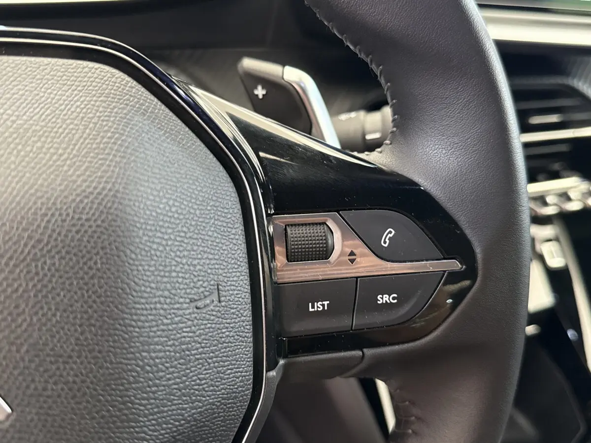 Gros plan sur les commandes multifonctions du volant cuir noir du Peugeot 2008 gris clair, version 2023.