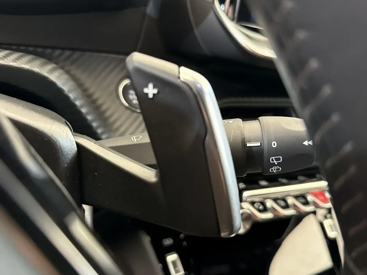 Gros plan sur la palette de changement de vitesse droite en plastique noir et chrome dans le Peugeot 2008 gris clair 2023.