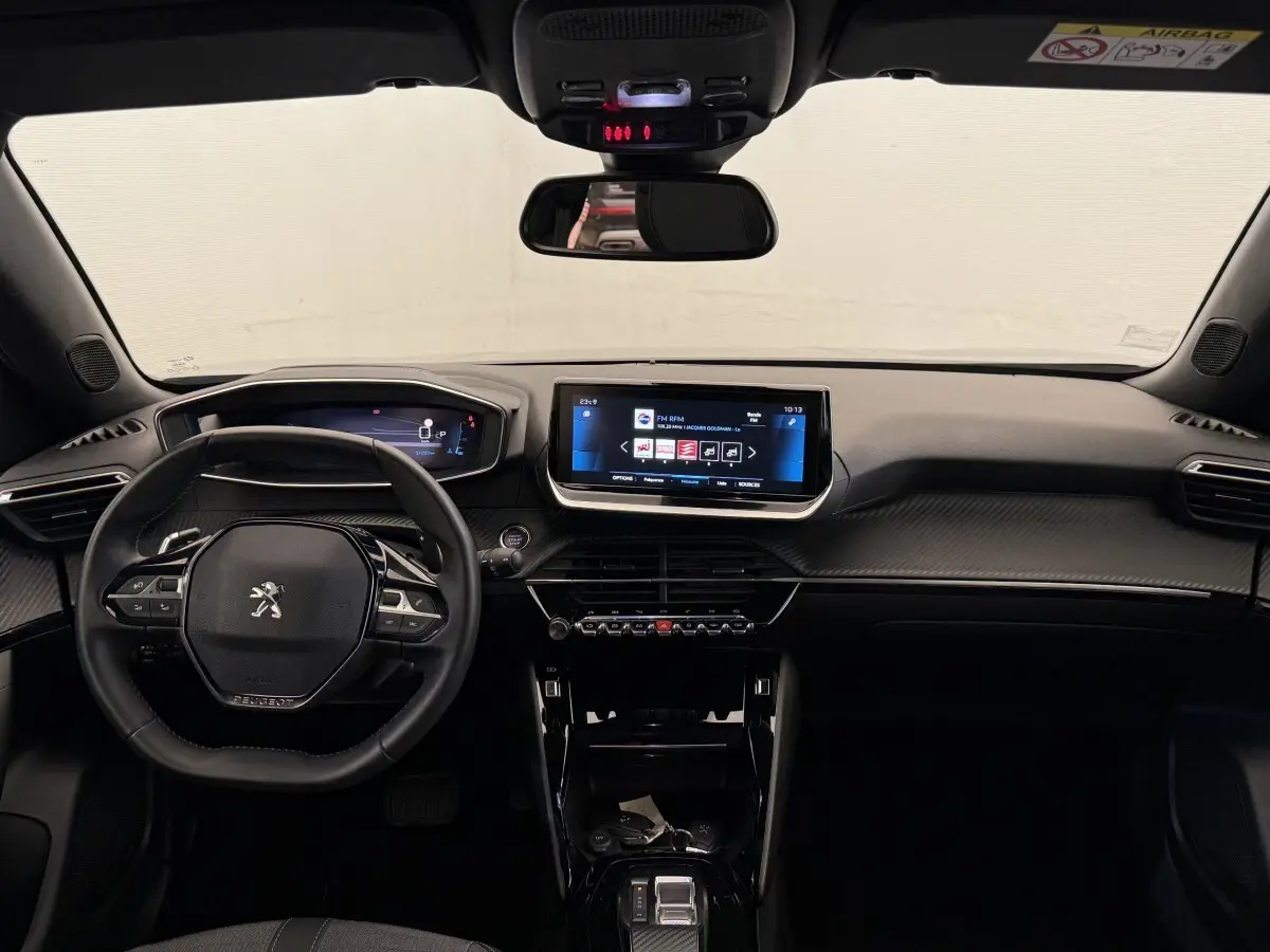Vue intérieure frontale du tableau de bord noir du Peugeot 2008 2023 avec écran tactile central et volant multifonction cuir.