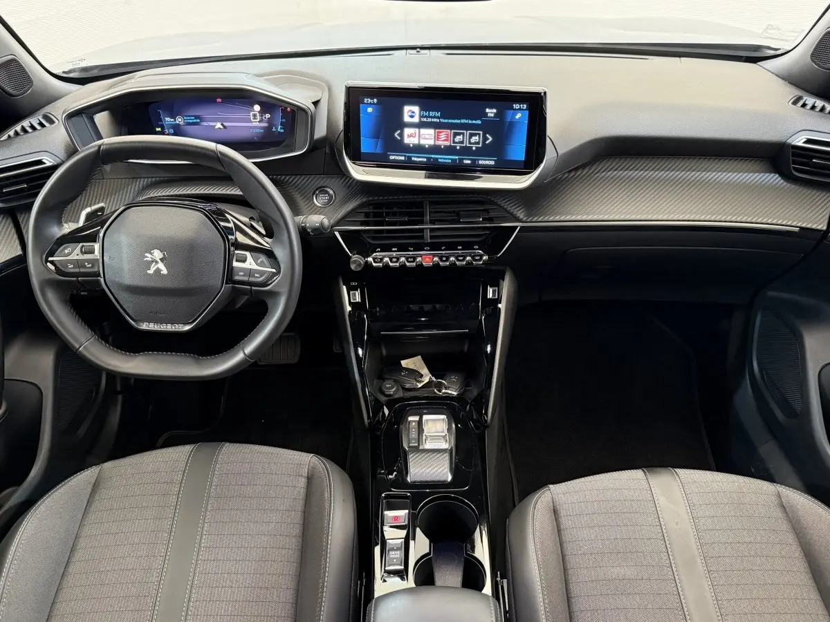 Vue intérieure avant du Peugeot 2008 2023, tableau de bord noir avec écran tactile central et volant compact cuir.