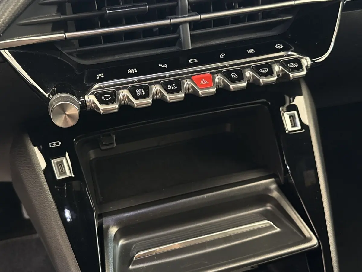 Vue rapprochée de la console centrale noire du Peugeot 2008 avec boutons chromés et ports USB visibles.