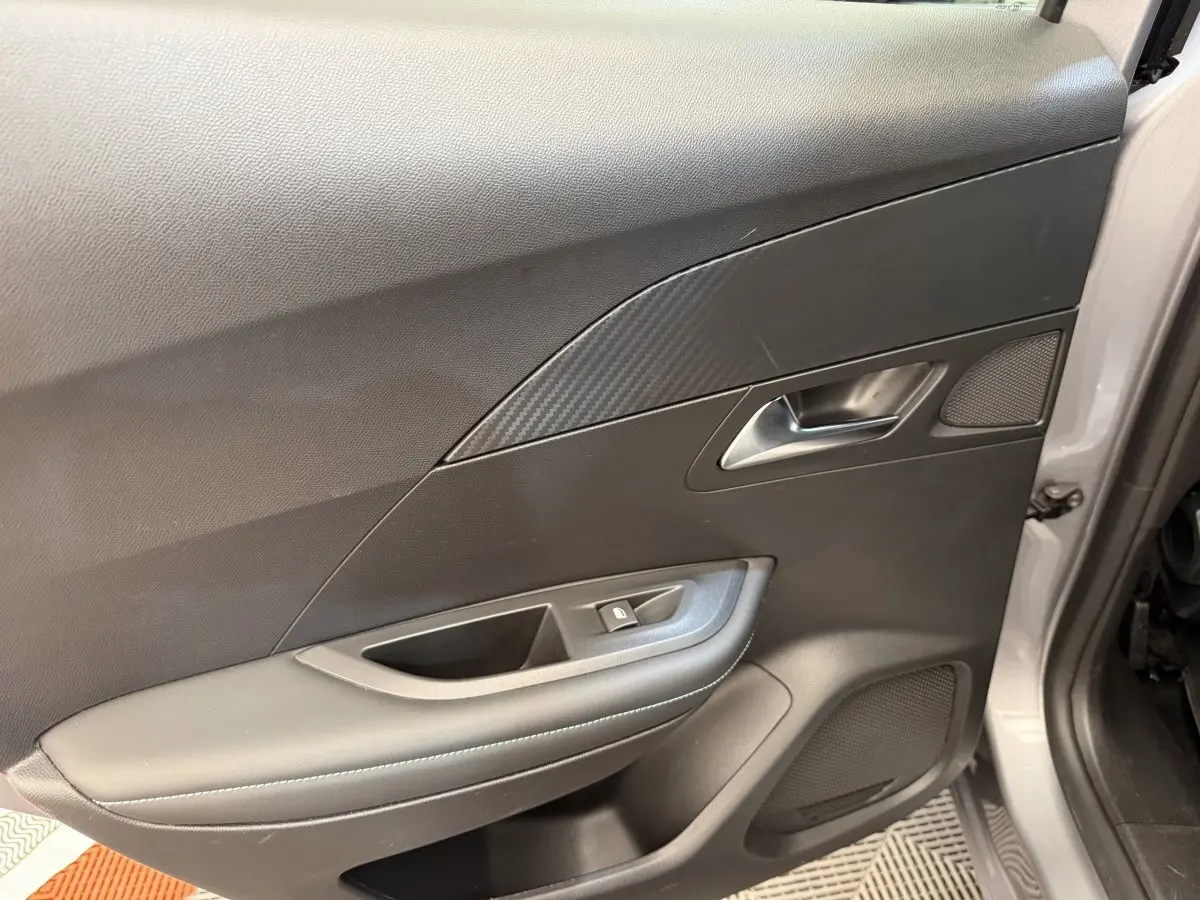 Vue rapprochée de la porte avant gauche gris clair du Peugeot 2008 avec habillage noir et insert effet carbone.