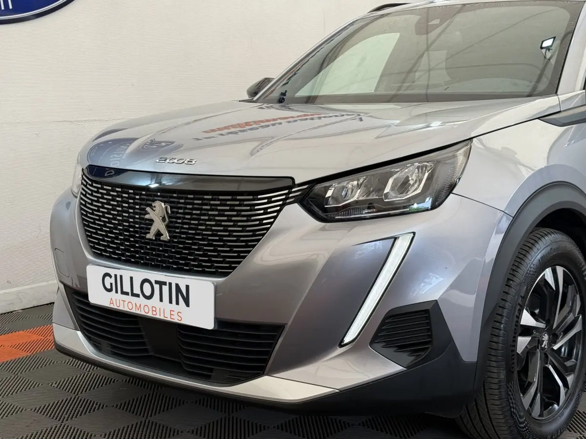 Vue 3/4 avant droit d’un Peugeot 2008 gris clair avec calandre noire et feux LED distinctifs.