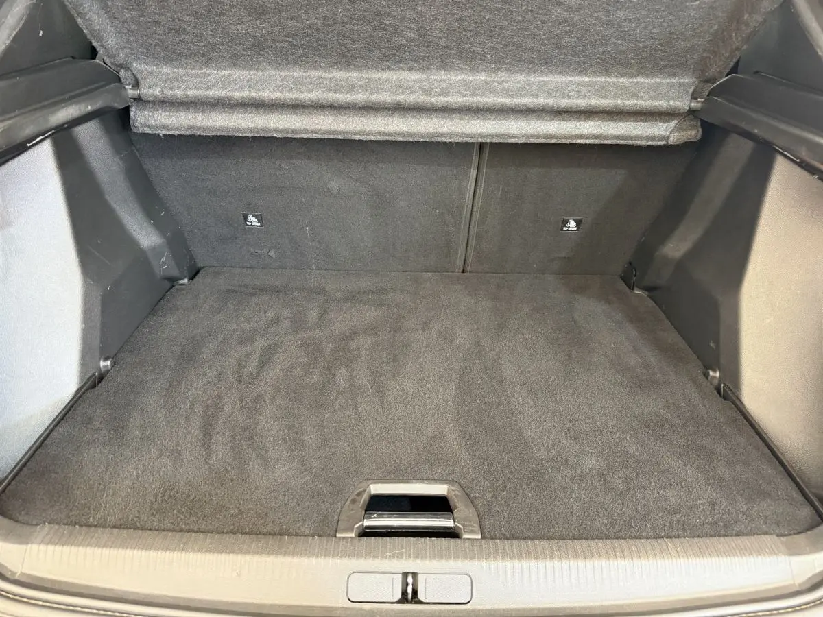 Coffre ouvert vu de l'arrière d'un Peugeot 2008 gris clair, montrant un espace de chargement propre et plat.