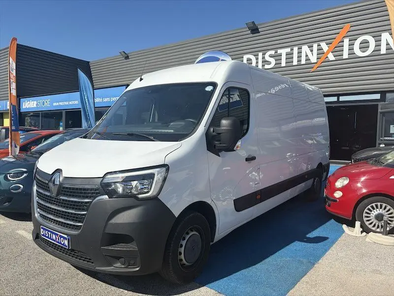 Renault Master blanc en 3/4 avant droit, grand utilitaire avec pare-chocs noir et calandre distinctive, stationné devant un concessionnaire.