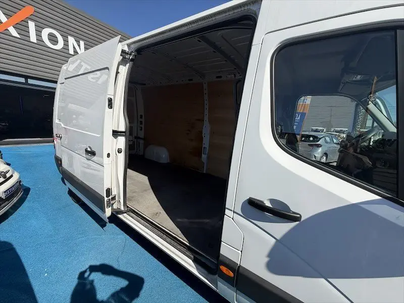 Vue de côté droit d’un Renault Master blanc avec porte latérale coulissante ouverte, montrant l’intérieur vide en bois.