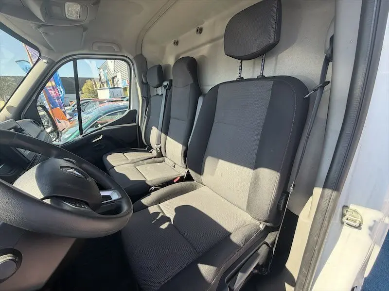 Vue intérieure côté conducteur du Renault Master blanc 2021, montrant les sièges avant en tissu gris et le volant.