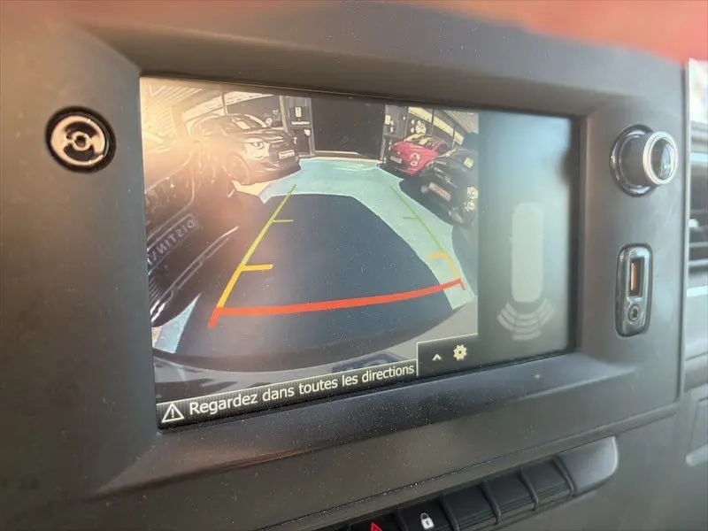 Écran de caméra de recul du Renault Master blanc montrant l'arrière avec lignes de guidage colorées en jaune et rouge.