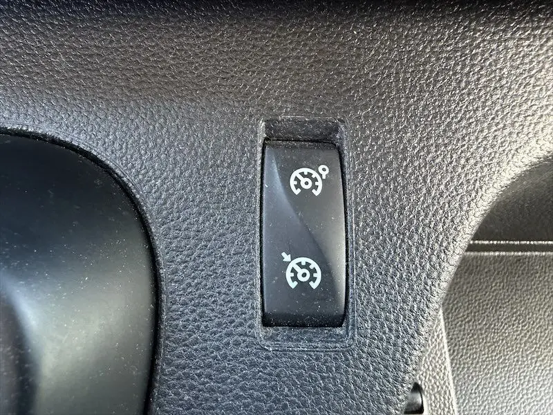 Gros plan sur le bouton de réglage du régulateur de vitesse dans l'habitacle noir du Renault Master blanc.