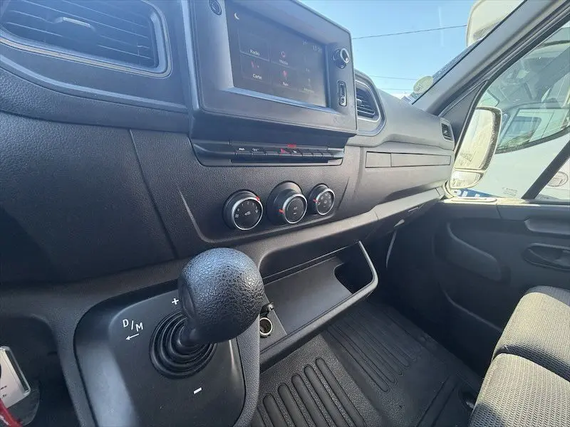 Vue intérieure côté passager du tableau de bord noir du Renault Master blanc, avec levier de vitesses et écran tactile.
