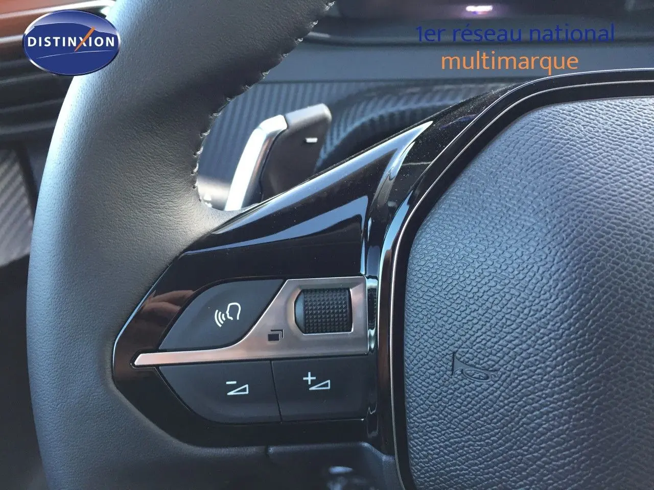 Gros plan sur les commandes du volant d'une Peugeot 208 gris selenium, mettant en valeur les boutons de volume et de téléphone.