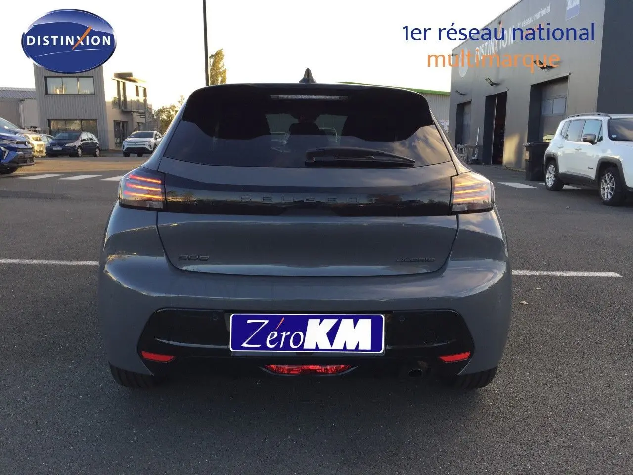 Vue arrière d'une Peugeot 208 gris selenium métal 2025 avec feux LED allumés sur parking extérieur.