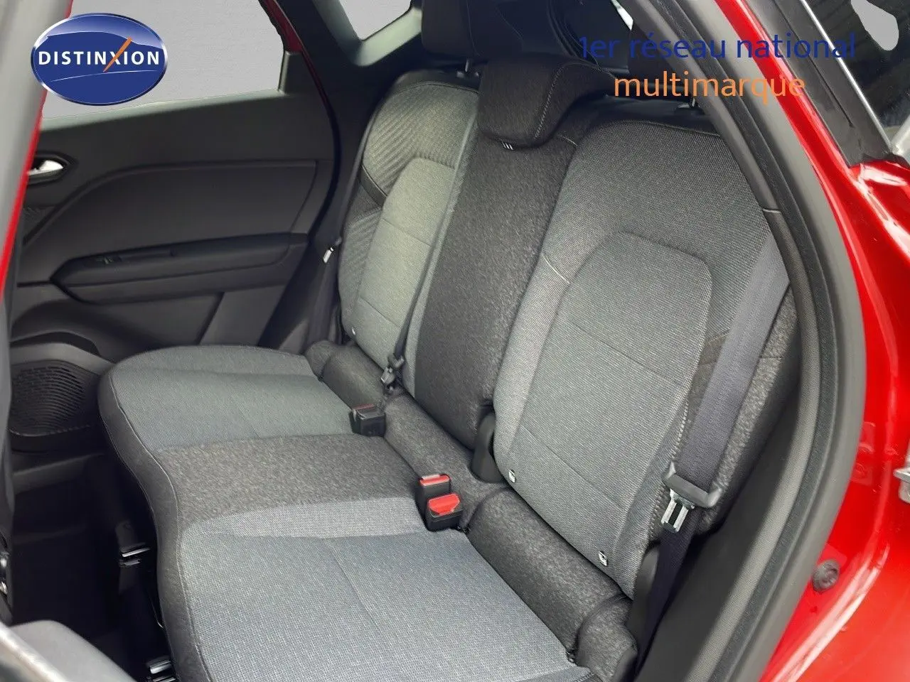 Vue intérieure arrière côté gauche du Renault Captur E-Tech hybride rouge passion, montrant les sièges tissu gris et noir.