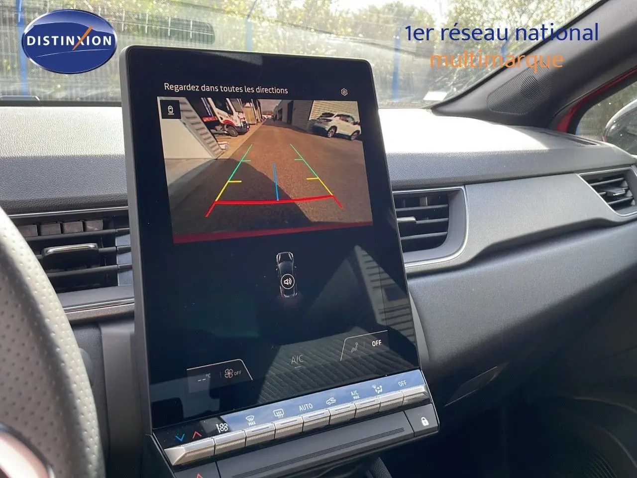 Vue intérieure du tableau de bord du Renault Captur rouge Passion 2025, avec écran tactile affichant la caméra de recul.