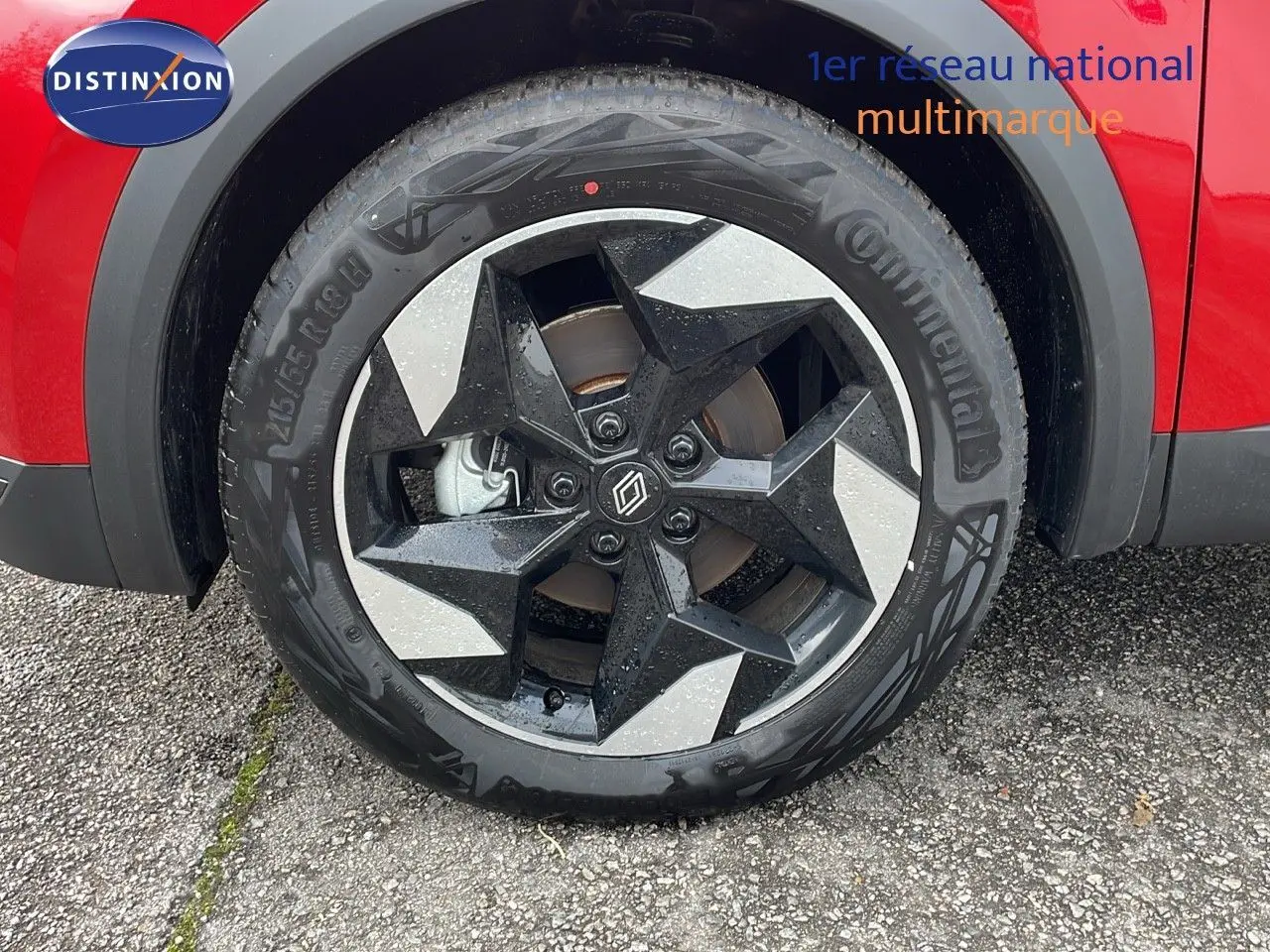 Gros plan sur la roue avant gauche du Renault Captur rouge passion avec jante noire et argentée au design moderne.