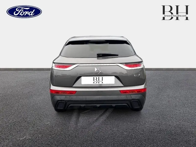 Vue arrière du DS7 Crossback gris Platinium avec feux LED et lunette arrière surteintée sur sol noir.