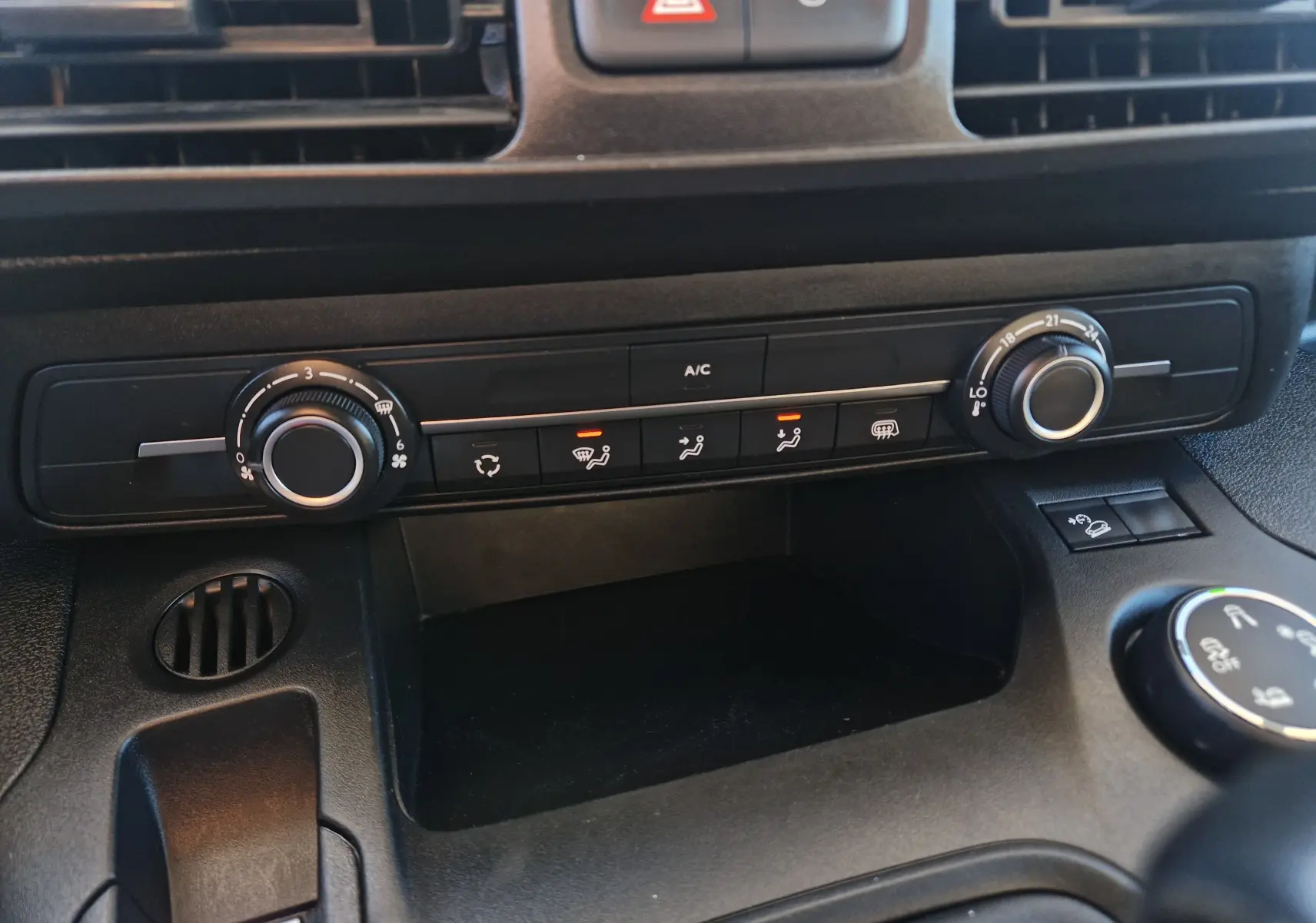 Gros plan sur la console centrale du Peugeot Partner blanc 2021, montrant les commandes de climatisation et ventilation.