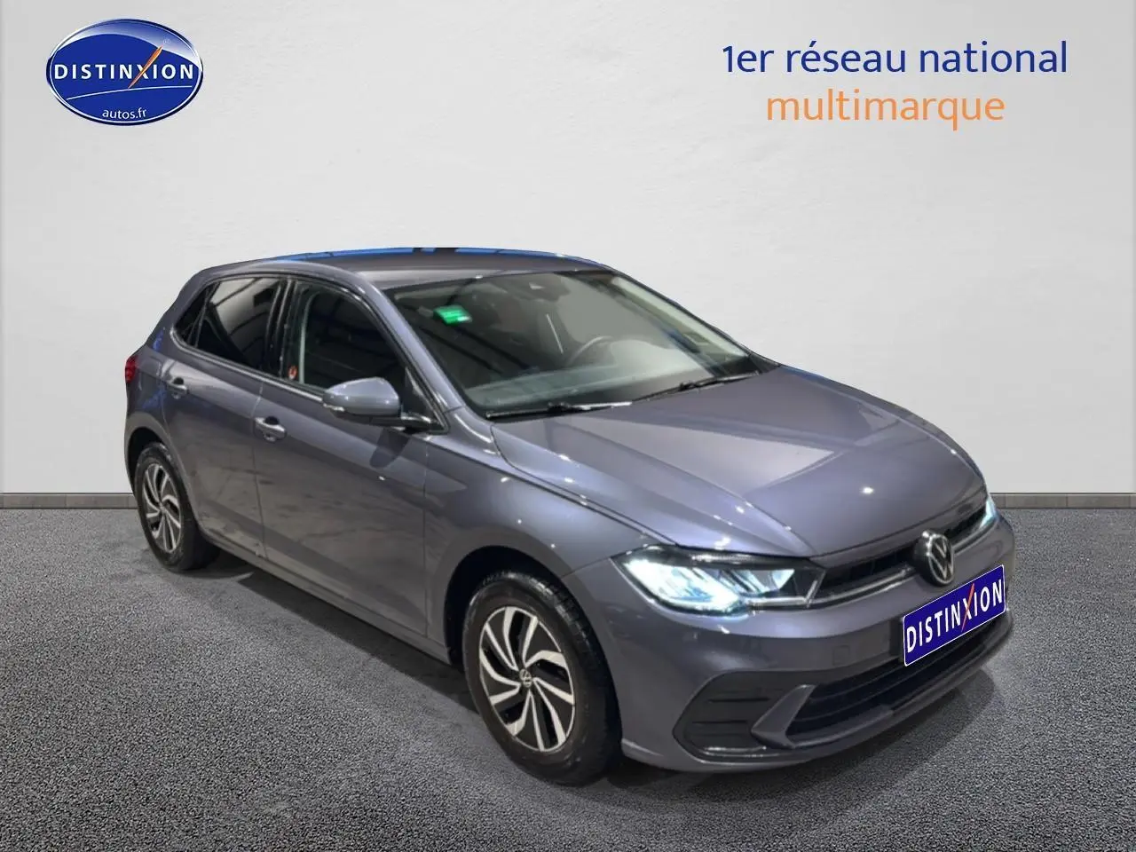 Volkswagen Polo gris cendre vue 3/4 avant droit avec phares LED allumés et jantes alliage 15 pouces.