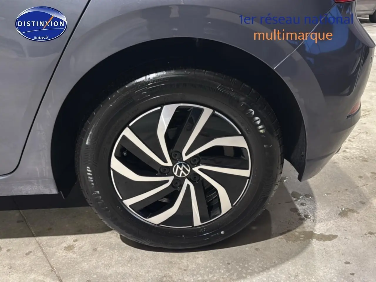 Gros plan sur la roue arrière droite d'une Volkswagen Polo gris cendre avec jante alliage noire et argent.