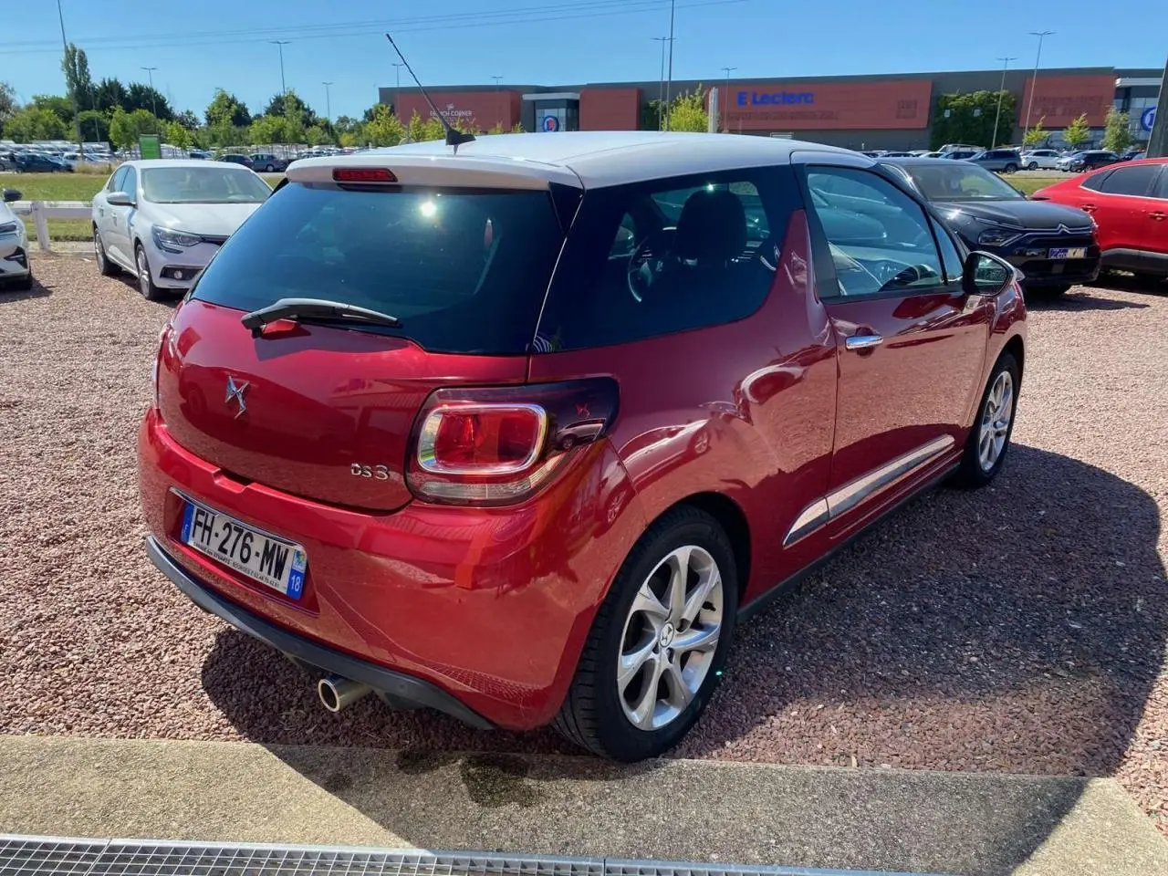 Vue 3/4 arrière droite d'une DS3 rouge à toit blanc avec jantes alliage et feux arrière distinctifs.