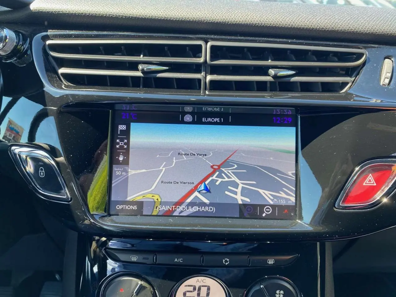 Tablette tactile centrale affichant la navigation du DS3 essence, avec commandes climatisation et bouton d’alerte rouge visibles.