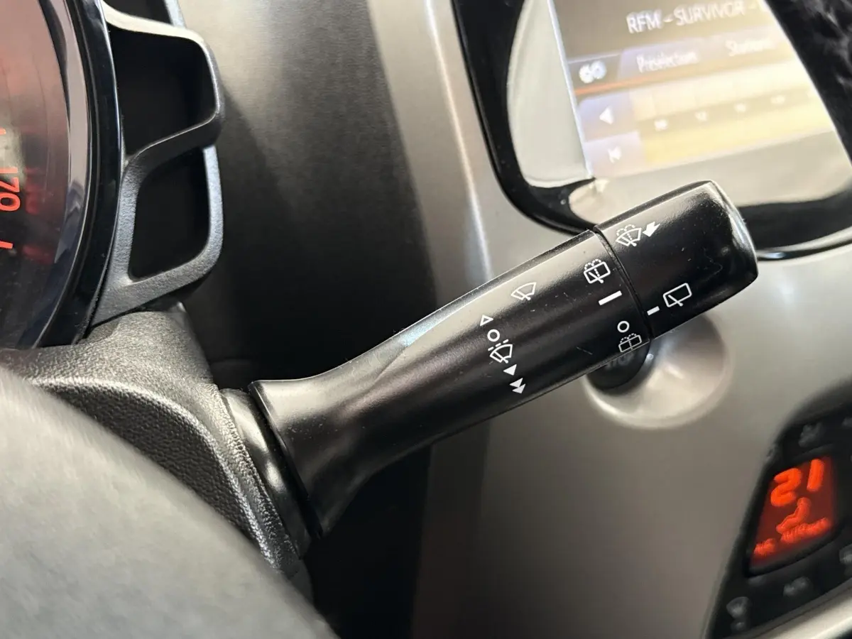 Gros plan sur la commande d’essuie-glaces à gauche du volant dans l’habitacle d’une Toyota Aygo gris clair de 2017.