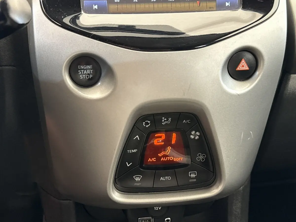 Vue rapprochée de la console centrale grise claire de la Toyota Aygo 2017, avec bouton de warning rouge visible.
