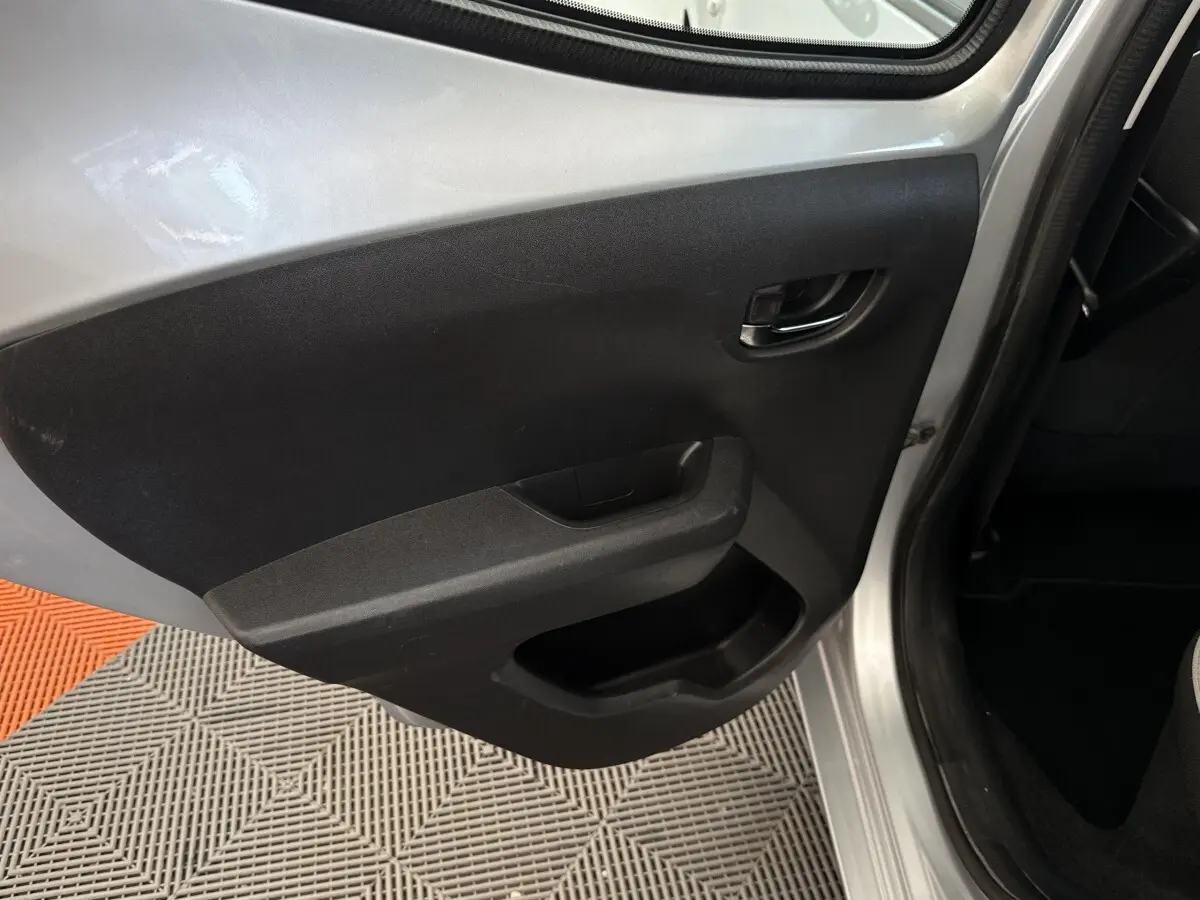 Vue rapprochée de la porte arrière gauche grise claire d’une Toyota Aygo 2017 avec panneau intérieur noir et poignée intégrée.