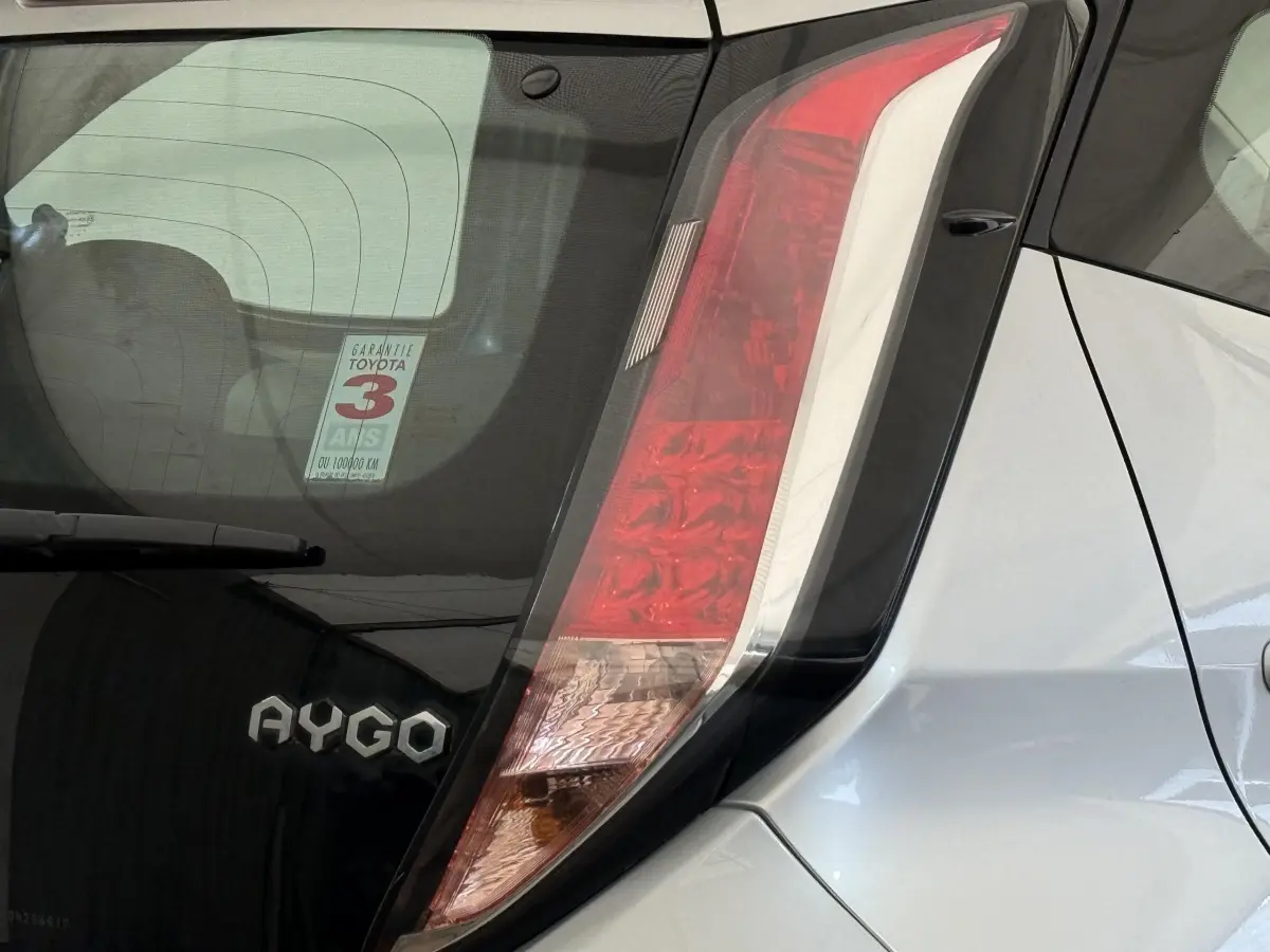 Gros plan sur l'arrière droit gris clair d'une Toyota Aygo 2017, mettant en valeur le feu arrière vertical et le logo AYGO.