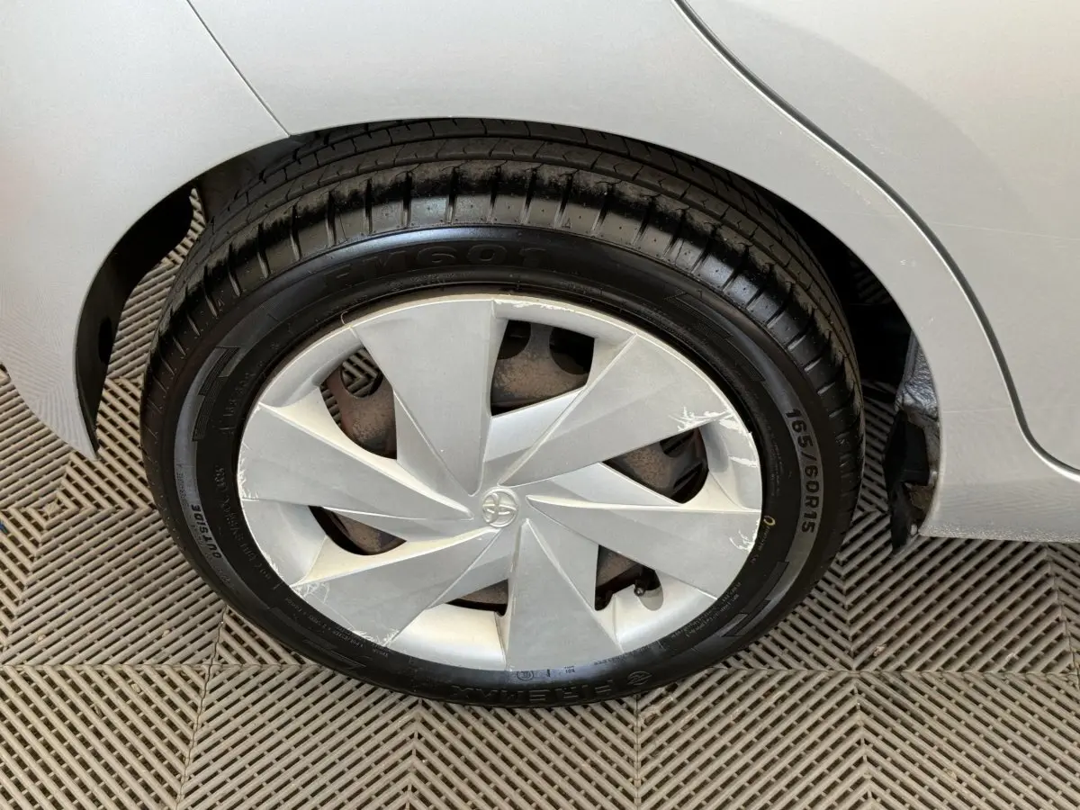 Gros plan sur la roue avant droite d'une Toyota Aygo gris clair, avec enjoliveur au design géométrique.