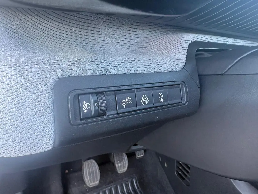 Détail des commandes situées à gauche sous le tableau de bord du Citroën C3 gris foncé, avec pédales manuelles visibles.