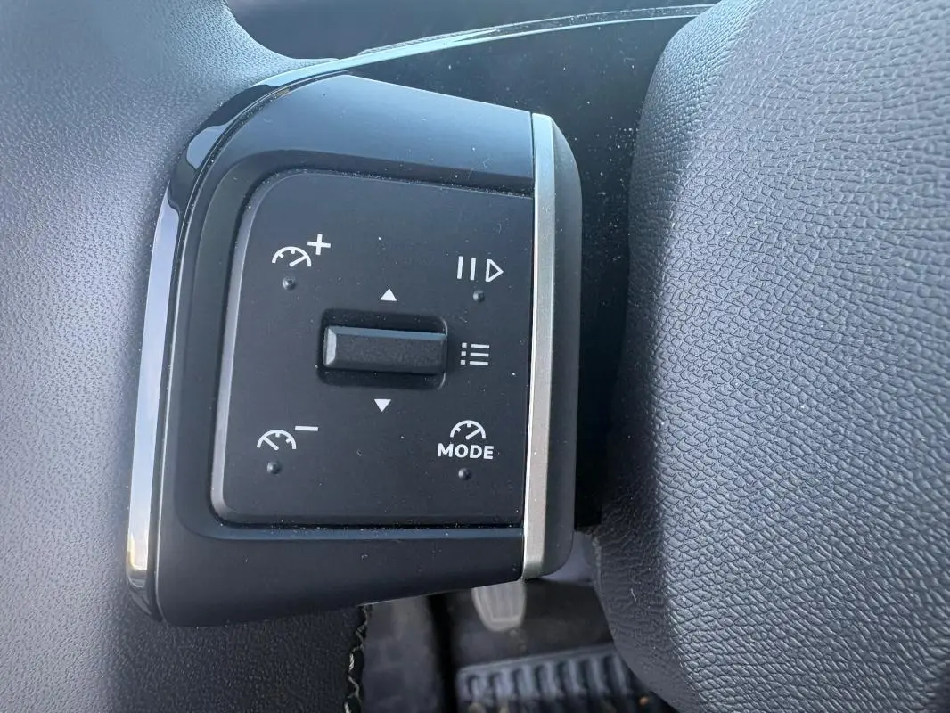 Gros plan sur les commandes au volant du Citroën C3 2025 gris foncé, avec réglages de vitesse et mode visible.