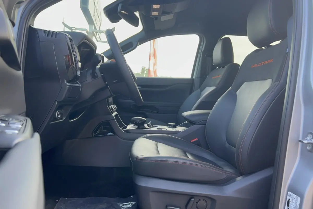 Vue intérieure côté conducteur du Ford Ranger Wildtrak 2026 avec sièges cuir noirs et surpiqûres orange WILDTRAK brodées.