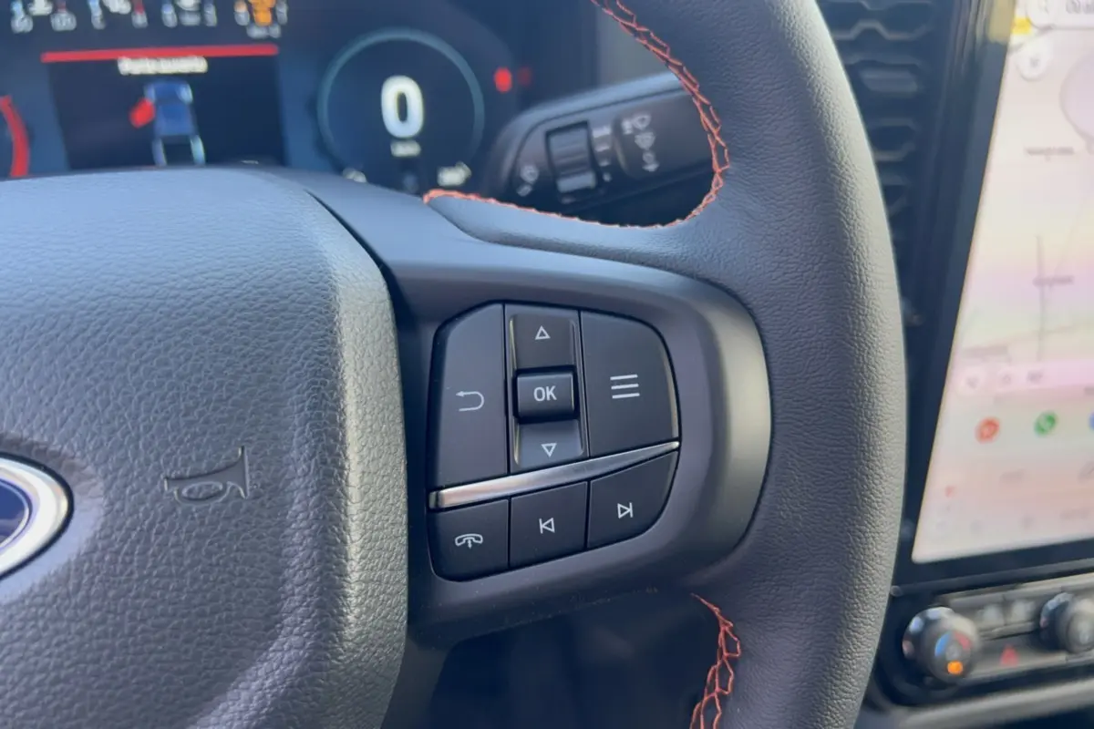 Gros plan sur les commandes multifonctions du volant en cuir noir avec surpiqûres rouges du Ford Ranger Wildtrak 2026.