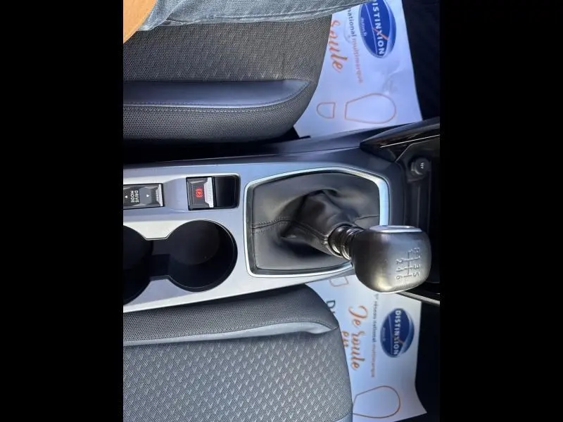 Vue rapprochée de la console centrale avec levier de vitesse manuel et sièges tissu gris du Peugeot 2008 gris Artense.
