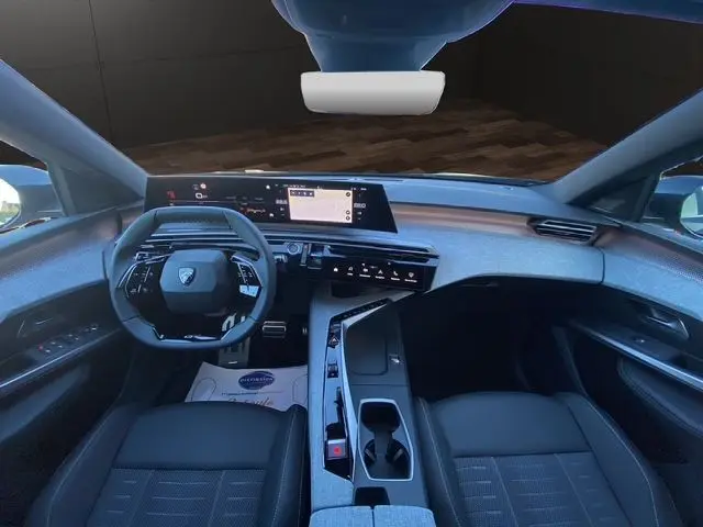 Vue intérieure avant du Peugeot 5008 Hybrid gris titane, mettant en valeur le tableau de bord numérique et la console centrale moderne.