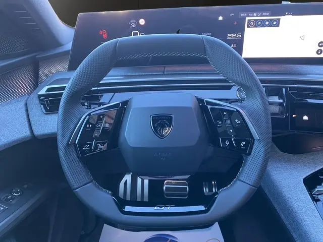 Vue rapprochée du volant noir du Peugeot 5008 Hybrid 145 GT 2025 avec tableau de bord numérique et commandes intégrées.