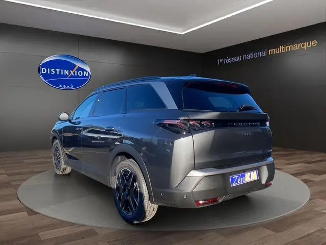 Peugeot 5008 Hybrid 145 gris titane, vue 3/4 arrière droit, jantes noires et feux arrière LED distinctifs.