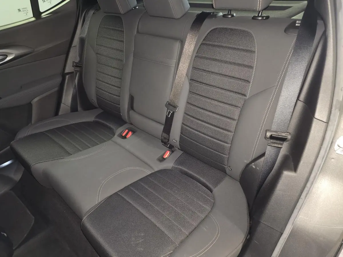 Vue intérieure de la banquette arrière noire de l'Alfa Romeo Tonale 1.3 PHEV avec ceinture de sécurité et accoudoir central.