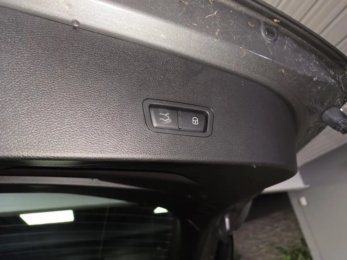 Gros plan sur le panneau noir intérieur du hayon ouvert de l'Alfa Romeo Tonale gris, avec boutons de fermeture et verrouillage.