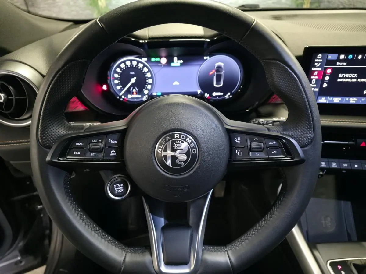 Vue centrée sur le volant sport en cuir noir de l'Alfa Romeo Tonale 2023 avec tableau de bord digital allumé.