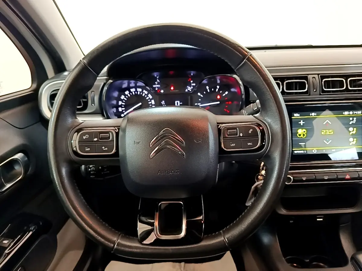 Vue intérieure centrée sur le volant cuir multifonctions d'une Citroën C3 2021 avec tableau de bord et écran tactile.