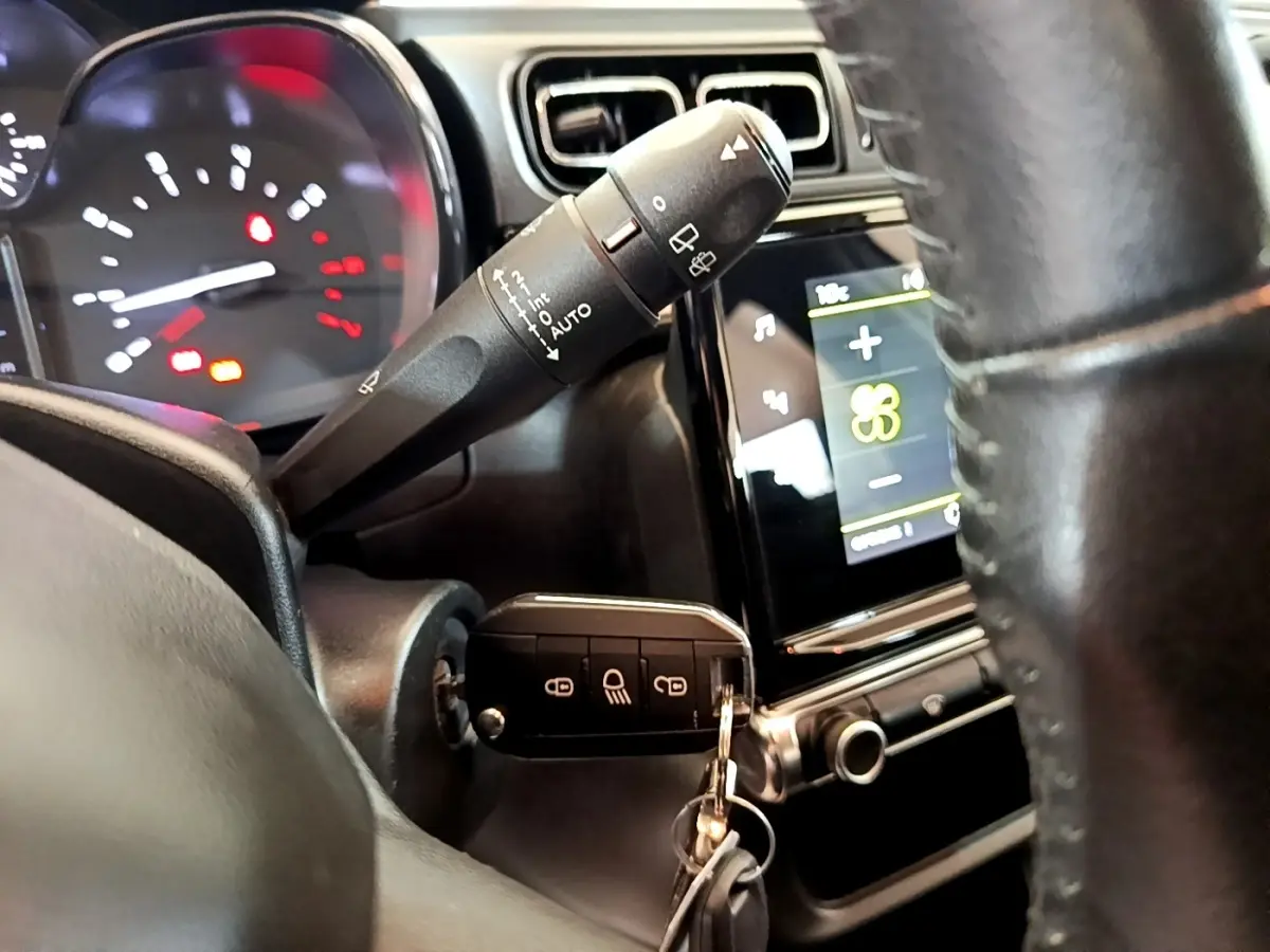 Vue rapprochée de l’intérieur de la Citroën C3 blanche, volant cuir et clé insérée dans le contacteur.